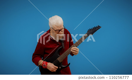Mature man plays the guitar, indulging in rock and roll for entertainment and embracing being forever young 110256777