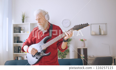Senior man plays the electric guitar, embodying a trendy grandpa, forever young at heart, embracing rock and roll 110257115