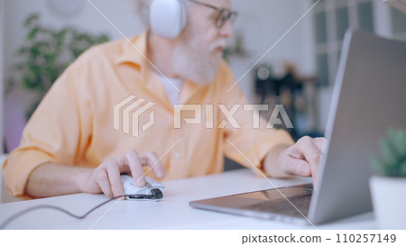 An excited senior man actively engages in an online video game, embodying the spirit of a contemporary grandpa 110257149