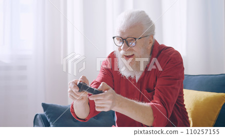 An excited mature man plays a video game, controlling the character with a joystick, demonstrating his contemporary grandpa vibe An excited mature man plays a video game, controlling the character with a joystick, demonstrating his contemporary grandpa vibe 110257155