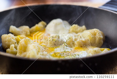 Cooked cauliflower, fried with eggs, in a frying pan with spices. Cooked cauliflower, fried with eggs, in a frying pan with spices. 110259111