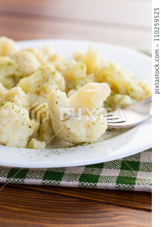 Cooked cauliflower, steamed, in a plate with spices . 110259525