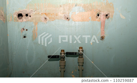 Against the background of an old wall with holes, there are two blocked water pipes. Concept for the start of renovation. Against the background of an old wall with holes, there are two blocked water pipes. Concept for the start of renovation. 110259887