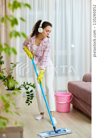 Happy woman singing and washing floor at living room, house chores. 110260852