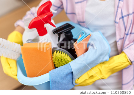 female hands in rubber gloves holding bucket with cleaning detergents and rags . close-up 110260890