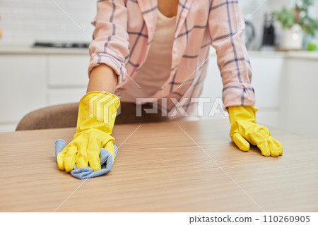 female hands cleaning and wiping wooden table with microfiber cloth. close-up. Housekeeping female hands cleaning and wiping wooden table with microfiber cloth. close-up. Housekeeping 110260905