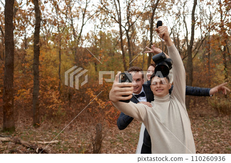 wedding photographer with bride and groom taking selfie with mobile phone in nature wedding photographer with bride and groom taking selfie with mobile phone in nature 110260936