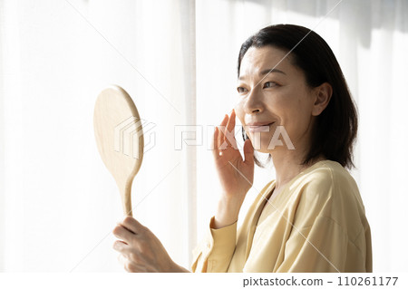 A woman troubled at seeing a mirror at the window side 110261177
