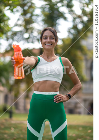 Smiling young woman with a bottle in hand feeling good after workout Smiling young woman with a bottle in hand feeling good after workout 110261914