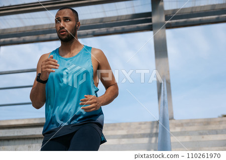 Man in blue tshirt running and looking concentrated 110261970