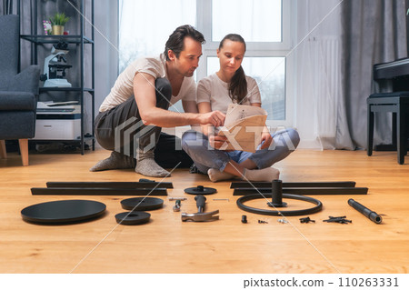 Husband and wife look through the instructions for assembling furniture together 110263331