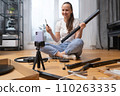 A vlogger girl records a video tutorial on furniture assembly on her phone. 110263335