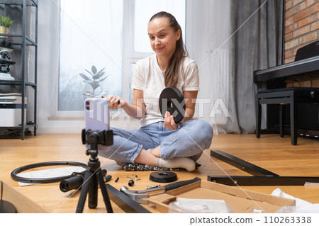 The girl is confused and consults by video link trying to assemble furniture. The girl is confused and consults by video link trying to assemble furniture. 110263338