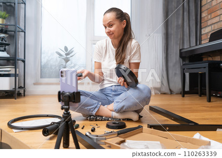 A girl does not understand how to assemble furniture and receives remote support A girl does not understand how to assemble furniture and receives remote support 110263339