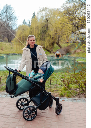 Happy boy sitting in a stroller with mom Happy boy sitting in a stroller with mom 110263442