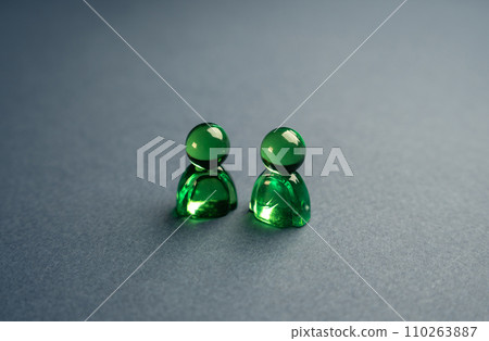 Two green glass figures of people. Concept of communication and business relationship. Assistance, cooperation and collaboration. A meeting. Friendly relations. Communication and discussion. Two green glass figures of people. Concept of communication and business relationship. Assistance, cooperation and collaboration. A meeting. Friendly relations. Communication and discussion. 110263887