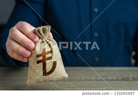 A man holds out a Turkish lira money bag. Deposits and savings. Economics and currency exchange, stock market. Banks and finance. Investments, fundraising. Funding and grants. Loans, mortgage. A man holds out a Turkish lira money bag. Deposits and savings. Economics and currency exchange, stock market. Banks and finance. Investments, fundraising. Funding and grants. Loans, mortgage. 110263897