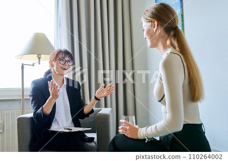 Mature female psychologist therapist working with young woman 110264002