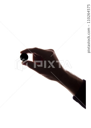 Young man hand with coin between his fingers - silhouette, concept Young man hand with coin between his fingers - silhouette, concept 110264575