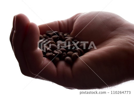 Man's hand a handful of coffee beans - silhouette Man's hand a handful of coffee beans - silhouette 110264773