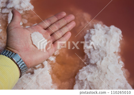 Male hand piece salt on pink water - extraction sea salt Male hand piece salt on pink water - extraction sea salt 110265010