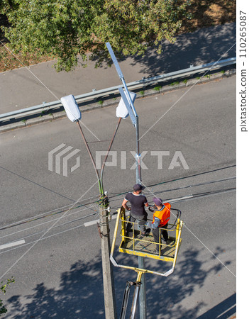 Workers installing a new street lamp and dismantling the old. Workers installing a new street lamp and dismantling the old. 110265087