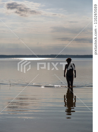 Silhouette of a woman going to swim in the lake Silhouette of a woman going to swim in the lake 110265089