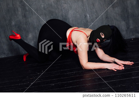 A masked woman in a dark room is a bandit A masked woman in a dark room is a bandit 110265611