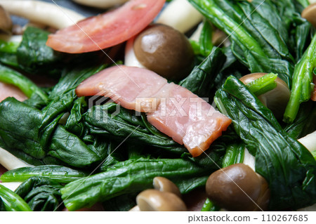 A close-up of the cooking scene of frying spinach and bacon in a frying pan. 110267685