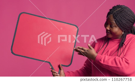African American beauty holding a red speech bubble mockup for text messages and notes in her right hand. Black lady nodding in agreement with the content of the word-bubble copyspace template. African American beauty holding a red speech bubble mockup for text messages and notes in her right hand. Black lady nodding in agreement with the content of the word-bubble copyspace template. 110267758