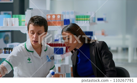 Experienced chemist in pharmacy using electronic thermometer on asian woman, checking temperature. Patient and healthcare practitioner during routine checkup, monitoring flu symptoms such as fever Experienced chemist in pharmacy using electronic thermometer on asian woman, checking temperature. Patient and healthcare practitioner during routine checkup, monitoring flu symptoms such as fever 110267791