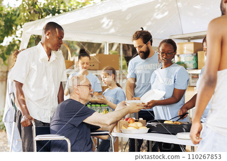 Diverse individuals donate free food to needy offering helping hand in fight against hunger and poverty. Volunteers provide support to homeless poor and disabled showcasing charitable efforts. 110267853