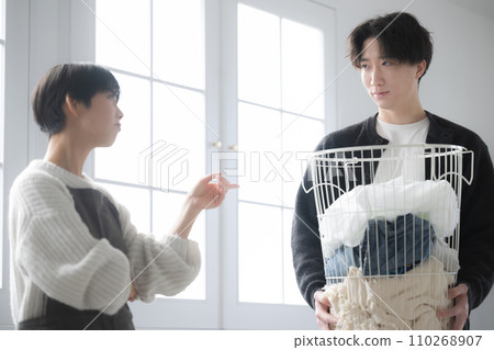 Husband carries laundry and wife gets irritated because housework is slow Husband carries laundry and wife gets irritated because housework is slow 110268907