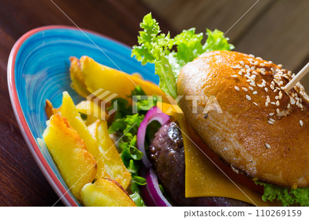 Cheeseburger with beef, tomato, cheese and lettuce at plate with french fries Cheeseburger with beef, tomato, cheese and lettuce at plate with french fries 110269159
