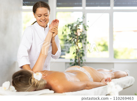 During massage, female physiotherapist stretch girl client arm to improve mobility of shoulder joint 110269463