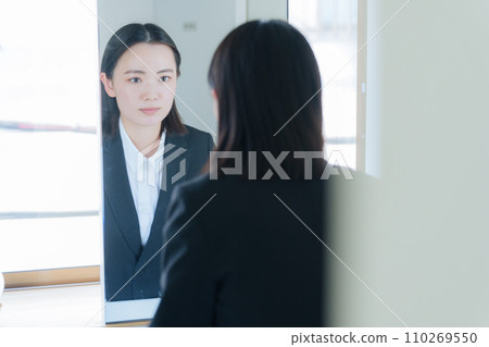 Young business woman looking in the bathroom mirror (beauty) 110269550