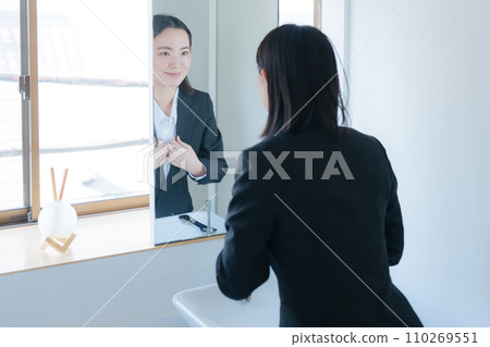 Young business woman looking in the bathroom mirror (beauty) 110269551