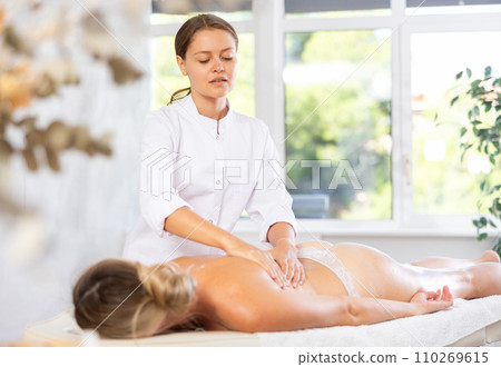 Young woman masseuse doing back massage 110269615