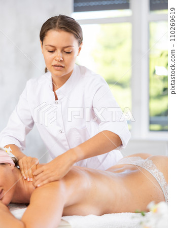 Female masseur works out shoulder and back problem area for female athlete client. 110269619