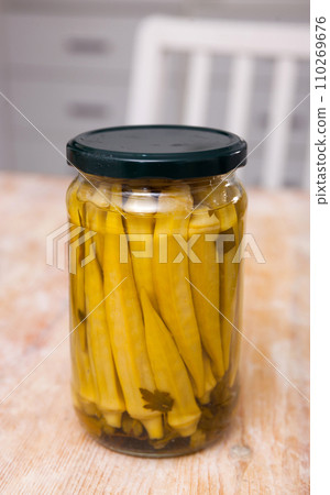 Glass jar with marinated okra on table 110269676