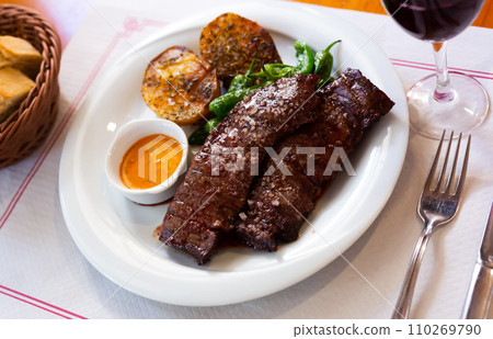 Roasted beef steak in chimichurri sauce served with baked potatoes. Spanish cuisine Roasted beef steak in chimichurri sauce served with baked potatoes. Spanish cuisine 110269790