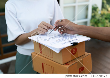 Young woman signature in document to receive package from professional delivery man at home Young woman signature in document to receive package from professional delivery man at home 110270374