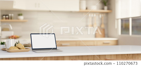 A laptop computer mockup on a white kitchen island or countertop in a modern, Scandinavian kitchen. A laptop computer mockup on a white kitchen island or countertop in a modern, Scandinavian kitchen. 110270673