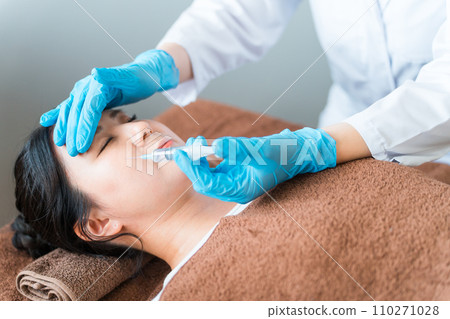 A patient receiving hyaluronic acid, Botox, and fat-dissolving injections on the cheeks and face and a cosmetic surgeon 110271028