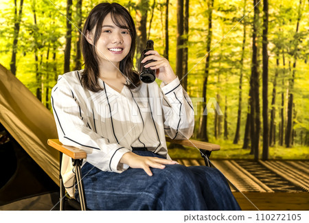 A young woman smiling with a beer in hand at glamping camp A young woman smiling with a beer in hand at glamping camp 110272105