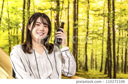 一位年輕女子在豪華露營地手裡拿著啤酒微笑 一位年輕女子在豪華露營地手裡拿著啤酒微笑 110272106