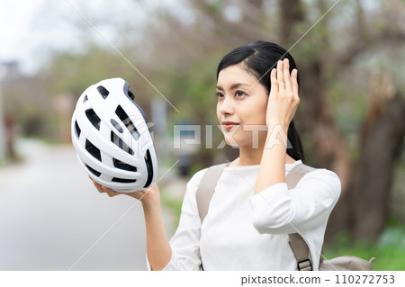 Young woman wearing a white cycling helmet 110272753