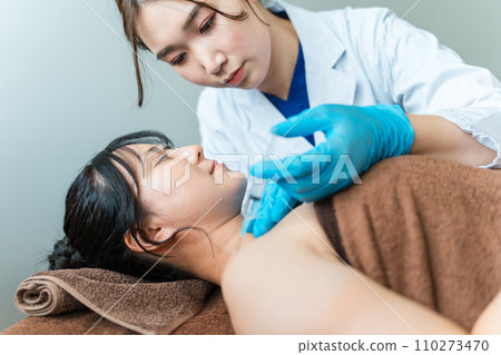 A woman and a doctor administering Botox/block injections to the shoulder (stiff shoulders) 110273470