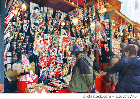 淺草的年終活動。淺草寺院內販售羽子板和食物的商店熙熙攘攘。 淺草的年終活動。淺草寺院內販售羽子板和食物的商店熙熙攘攘。 110273776