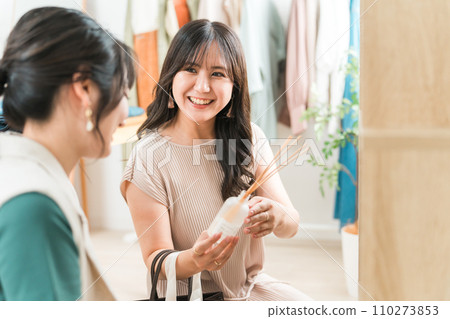 A woman enjoys shopping for interior fragrances at a general store, apparel shop, and clothing store. 110273853